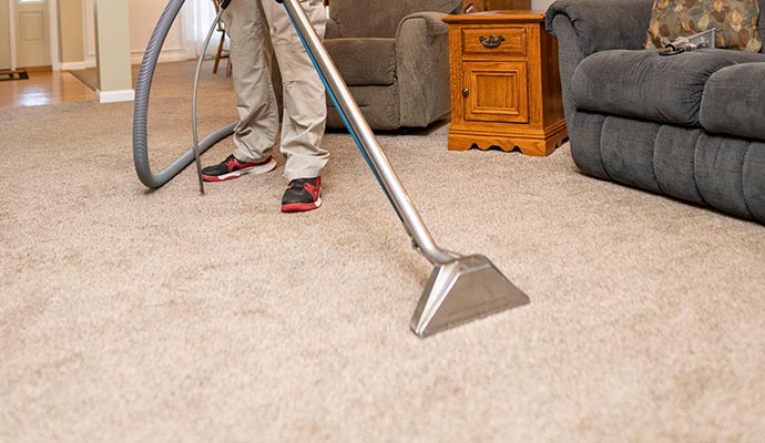 Person cleaning carpet with equipment 