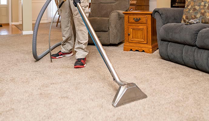 man cleaning a wool beige color carpet in the living room