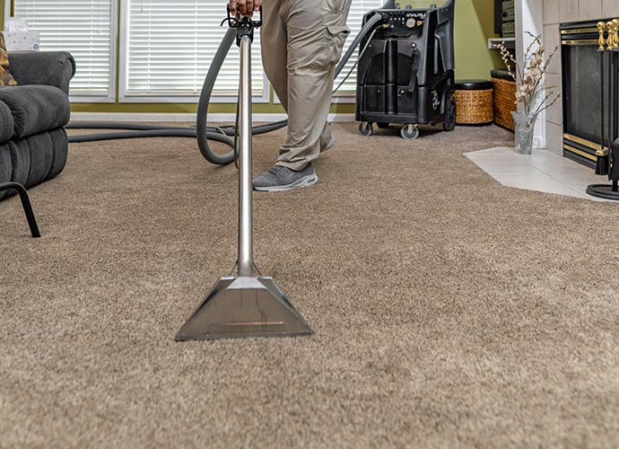 Person cleaning carpet with equipment