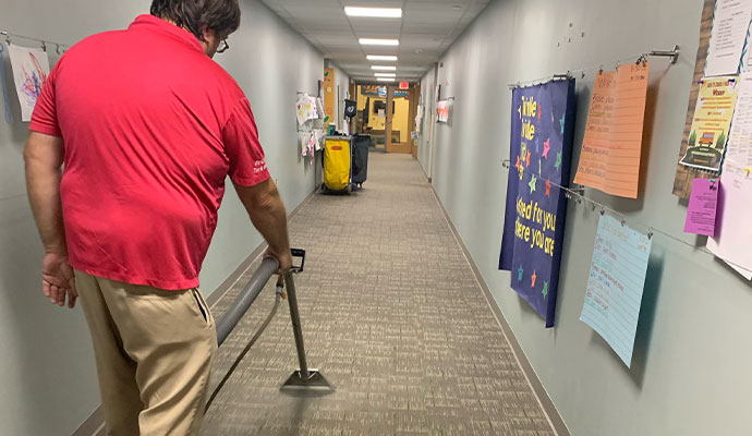 Technician cleaning hallway carpet with steam wand