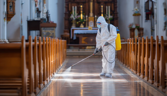 Technician spraying disinfectant in church sanctuary
