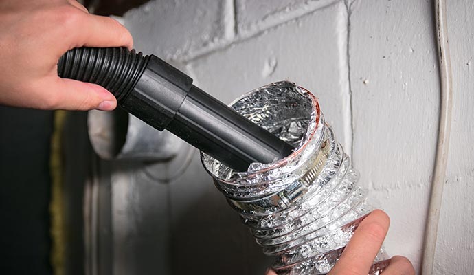 Person cleaning duct with equipment