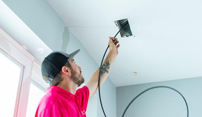 Person cleaning duct with equipment