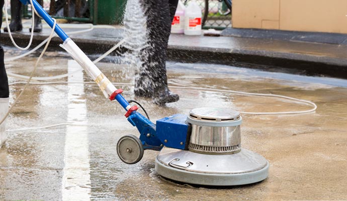 Person cleaning floor with equipment