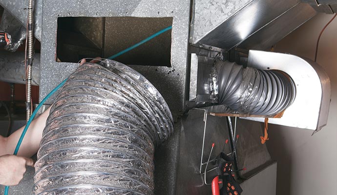 Person cleaning duct with equipment