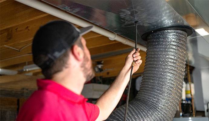 Person cleaning duct with equipment