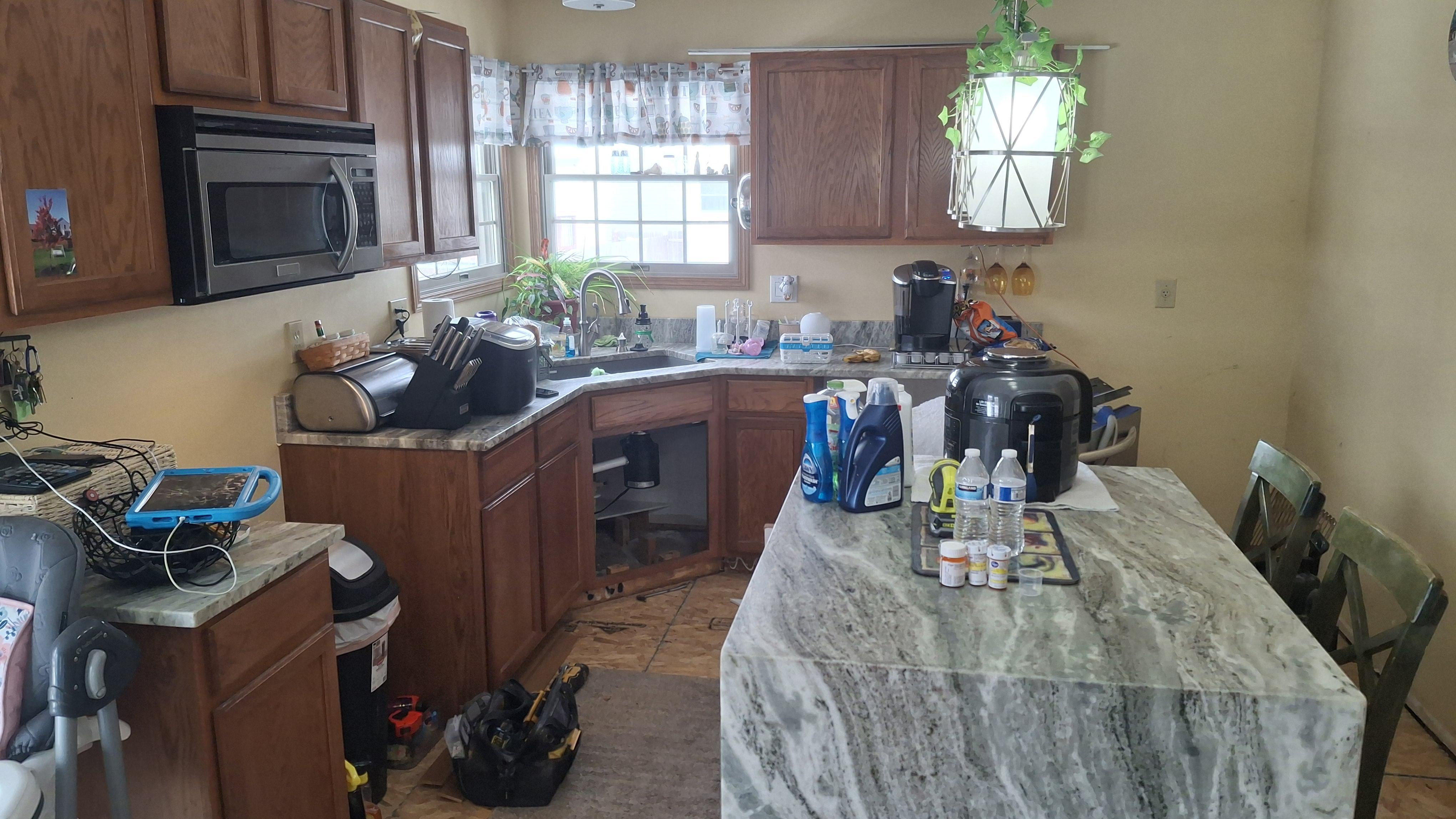 Aligning and reinstalling dark wood cabinetry trim during a residential kitchen restoration project.