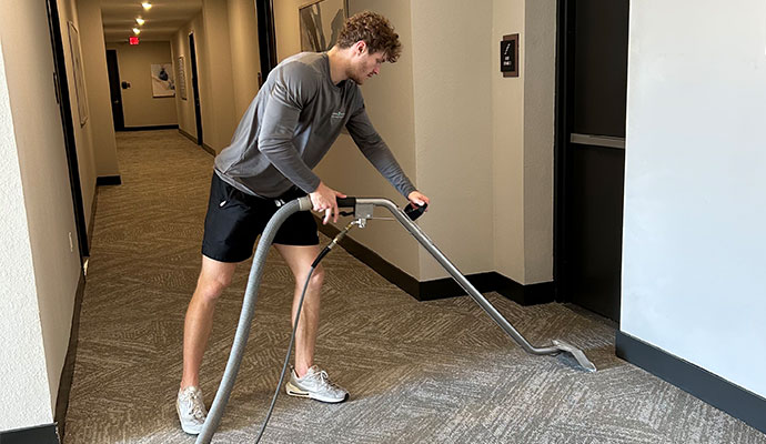 Person cleaning carpet with wand