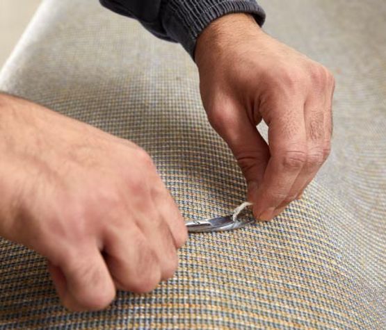 Person repairing damaged carpet using professional equipment
