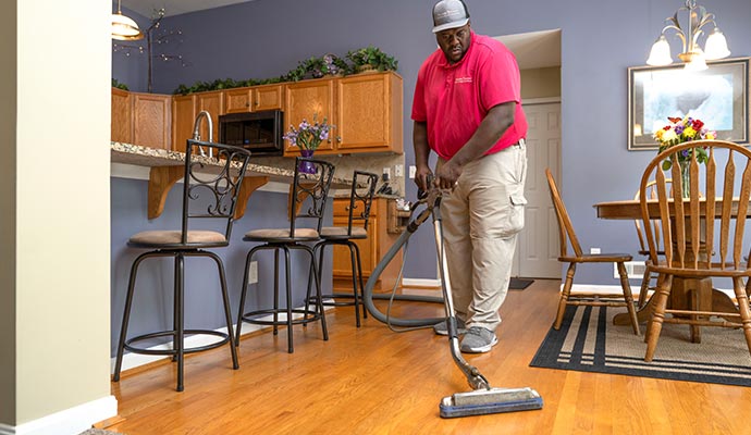 Purple dressed worker cleaning hardwood floor