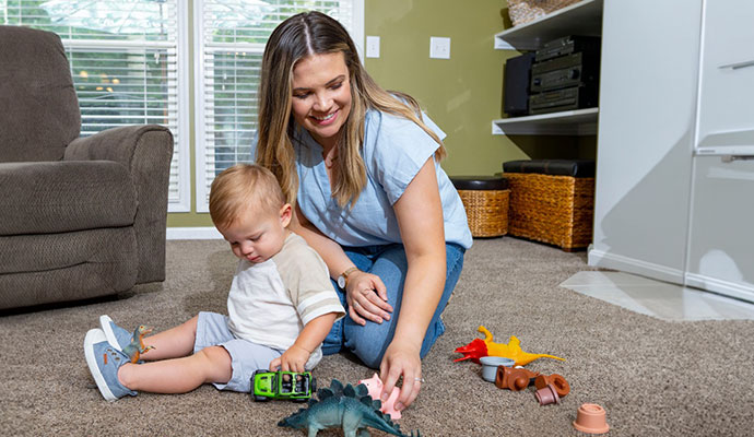 A mother playing with her child in a clean living room.