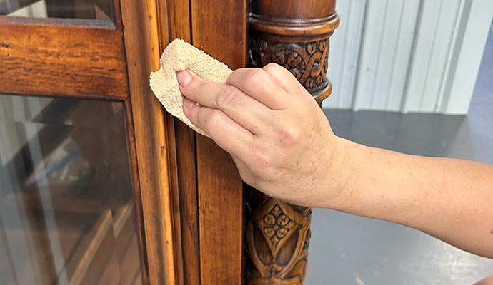 Skilled professional cleaning a carved wooden cabinet using a soft cloth
