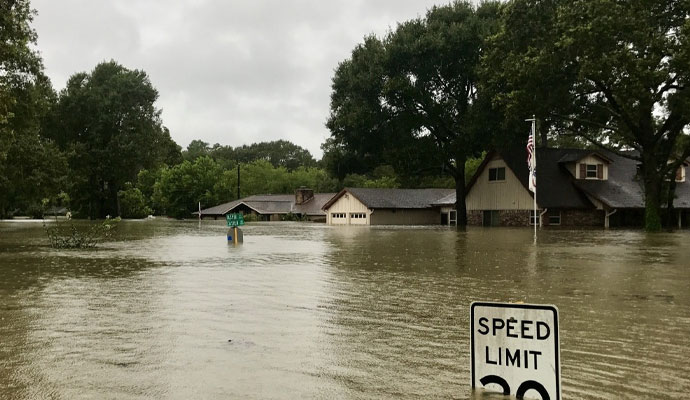 Flooded residential area with houses and signs.