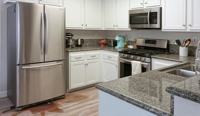 Modern refrigerator leaking water on kitchen floor