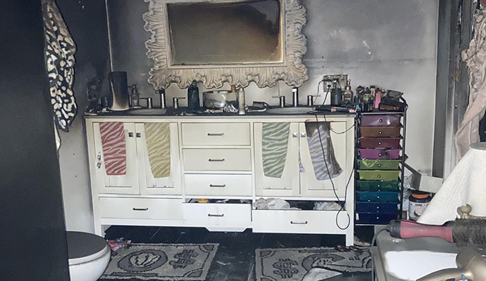Soot and smoke damage on bathroom vanity, mirror, and walls