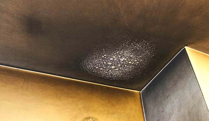 Soot-stained ceiling corner with moisture condensation