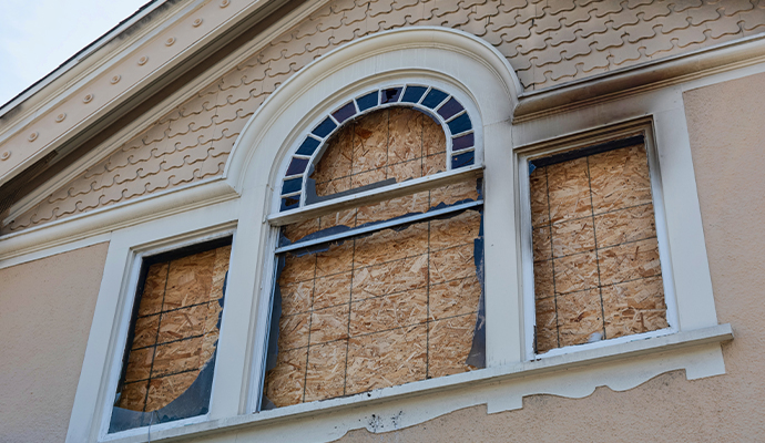 Broken windows boarded up with plywood on building