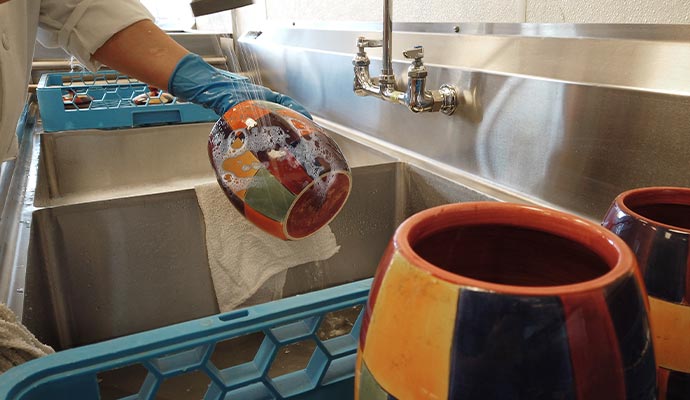 Person washing a pot in the kitchen sink