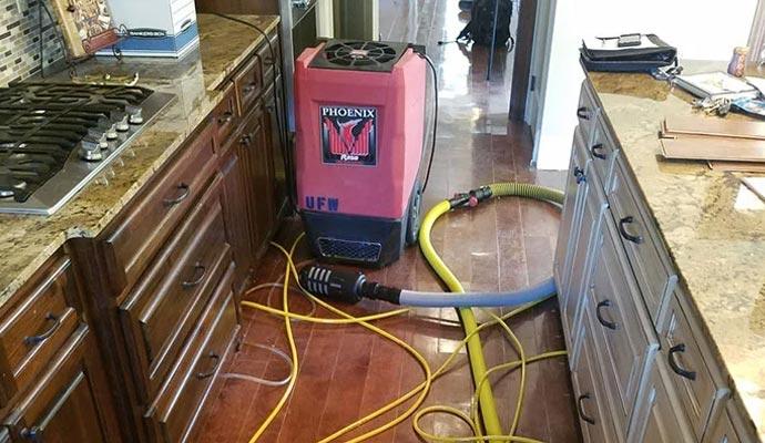 Water damaged kitchen floor undergoing restoration service