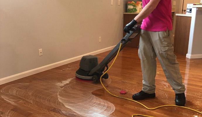 Person cleaning wooden floor with equipment
