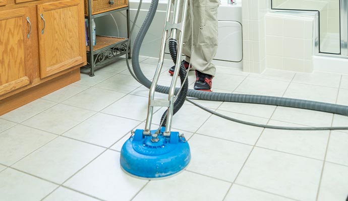 Worker cleaning white colored tile by machine